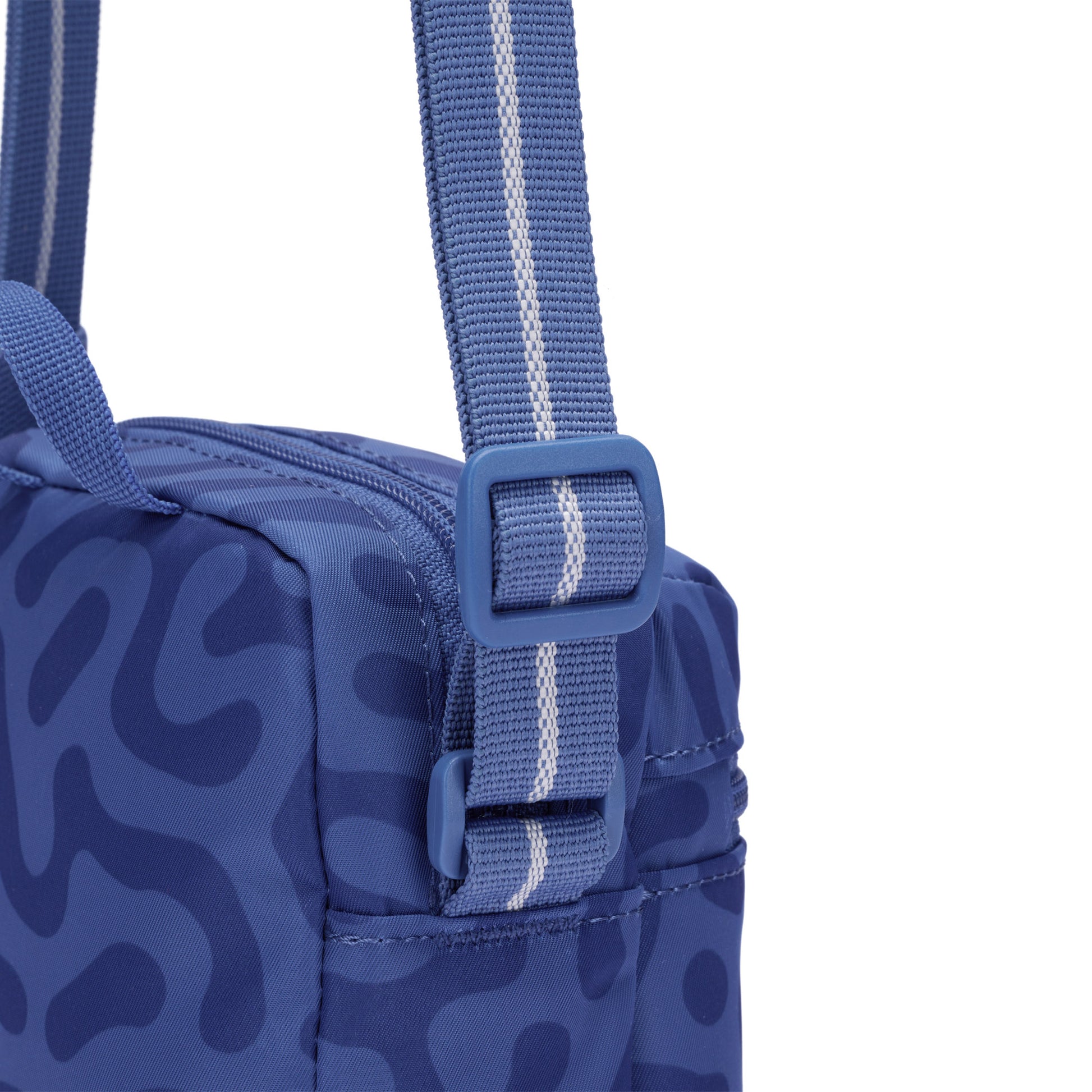 Close-up of the Pacsafe® GO Anti-Theft Micro Crossbody in blue with a striped strap and RFID-blocking pocket.