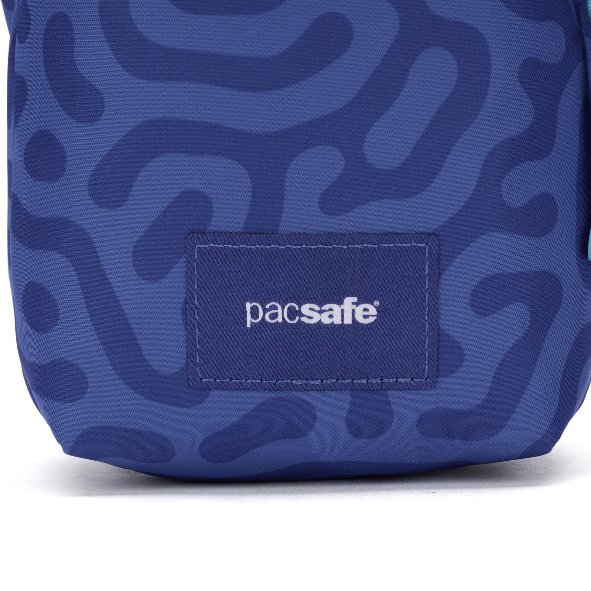 Close-up of Pacsafe® GO Anti-Theft Micro Crossbody in blue with abstract pattern, logo, and recycled polyester.