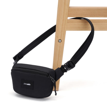 A black Pacsafe® GO Anti-Theft Micro Sling is secured around the leg of a light wooden chair.