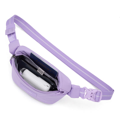 The Pacsafe® GO Anti-Theft Micro Sling in lavender polyester opens to reveal a passport, phone, and white object.