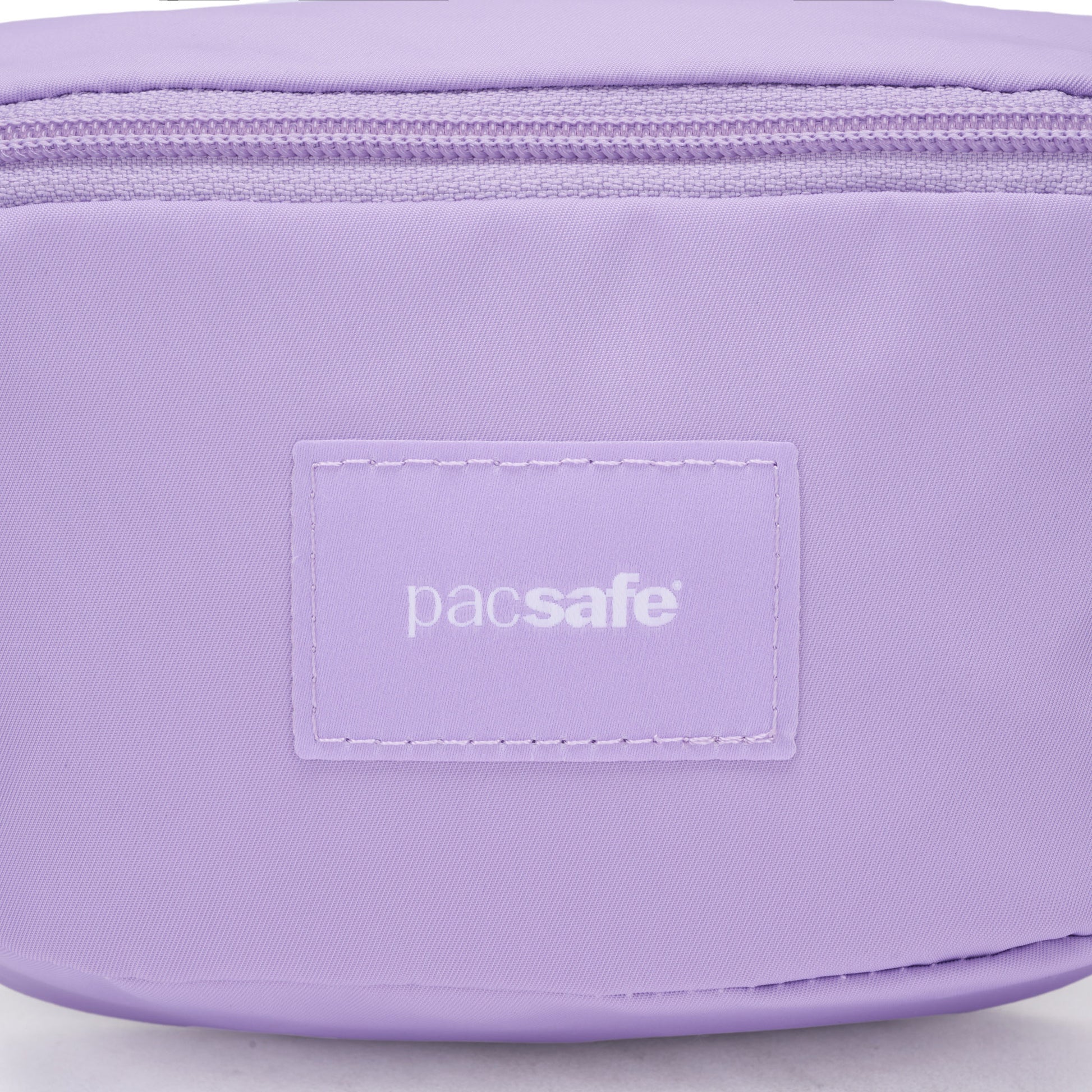 Close-up of a light purple Pacsafe® GO Anti-Theft Micro Sling pouch with zipper and stitched brand label.