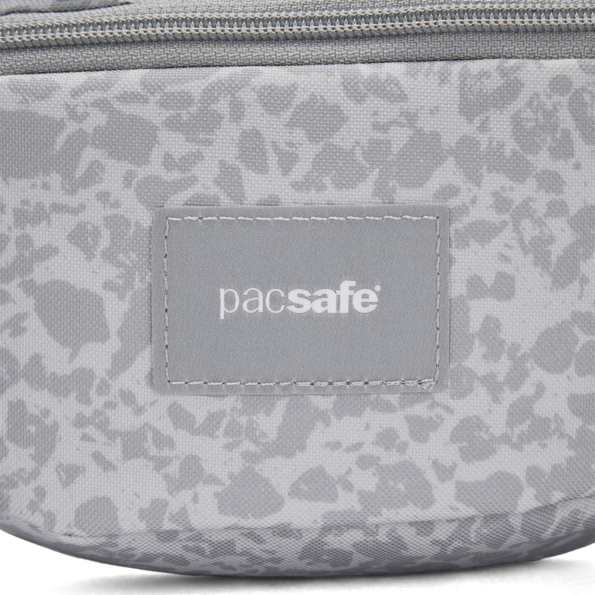 Close-up of the Pacsafe® GO Anti-Theft Micro Sling in gray with logo patch and top zipper.