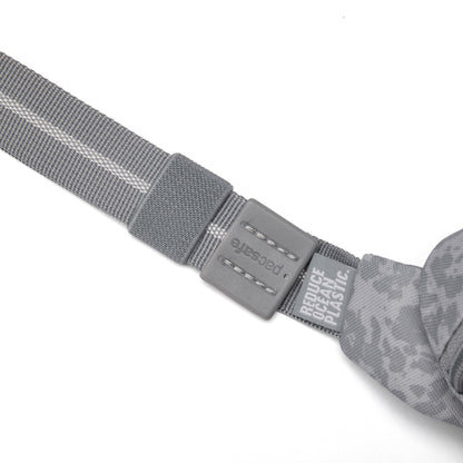 Close-up of Pacsafe® GO Anti-Theft Micro Sling’s gray recycled strap with plastic buckle and printed text.
