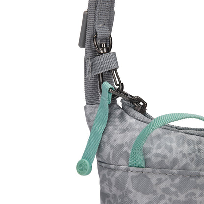 Close-up of Pacsafe® GO Anti-Theft Tech Crossbody in gray with teal zipper pull and strap detail.