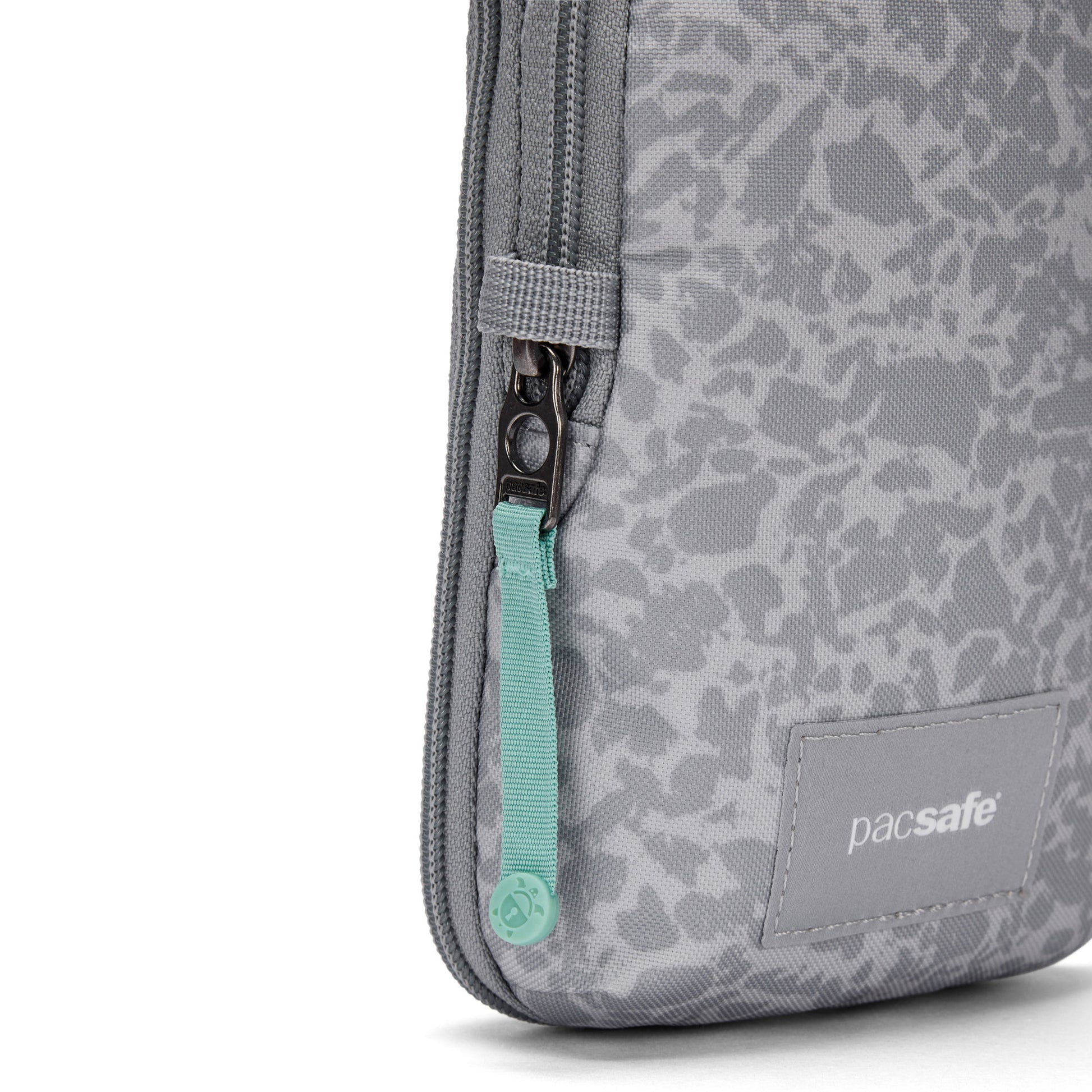 Close-up of the Pacsafe® GO Anti-Theft Tech Crossbody with teal zipper pull and subtle patterned gray fabric.