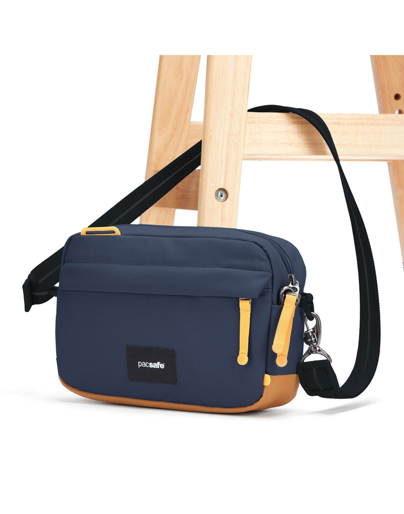 Pacsafe® GO Anti-Theft Crossbody Bag in coastal blue colour with shoulder strap secured to a chair leg.