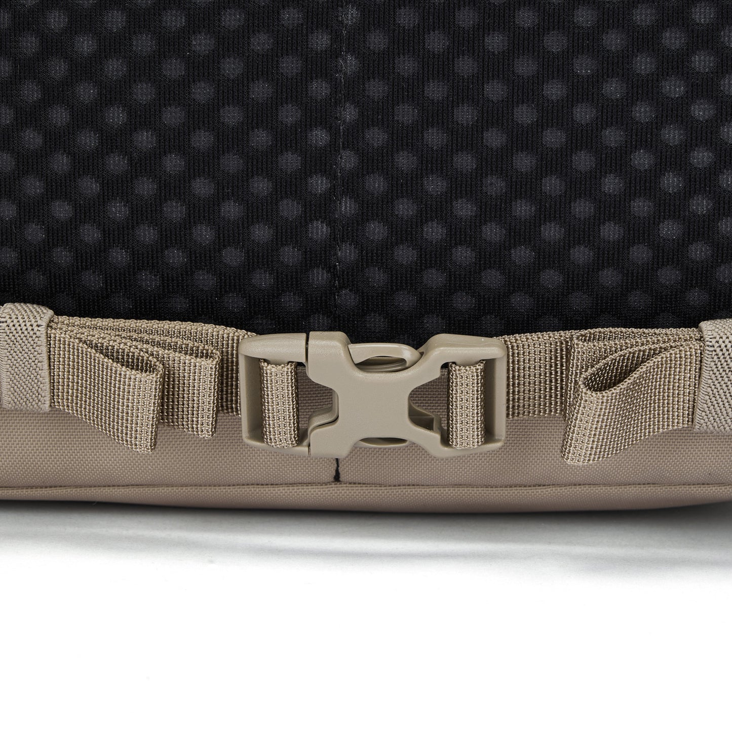 Close-up of a beige buckle on the Pacsafe® V 16L Anti-theft All-Around Backpack strap against black background.