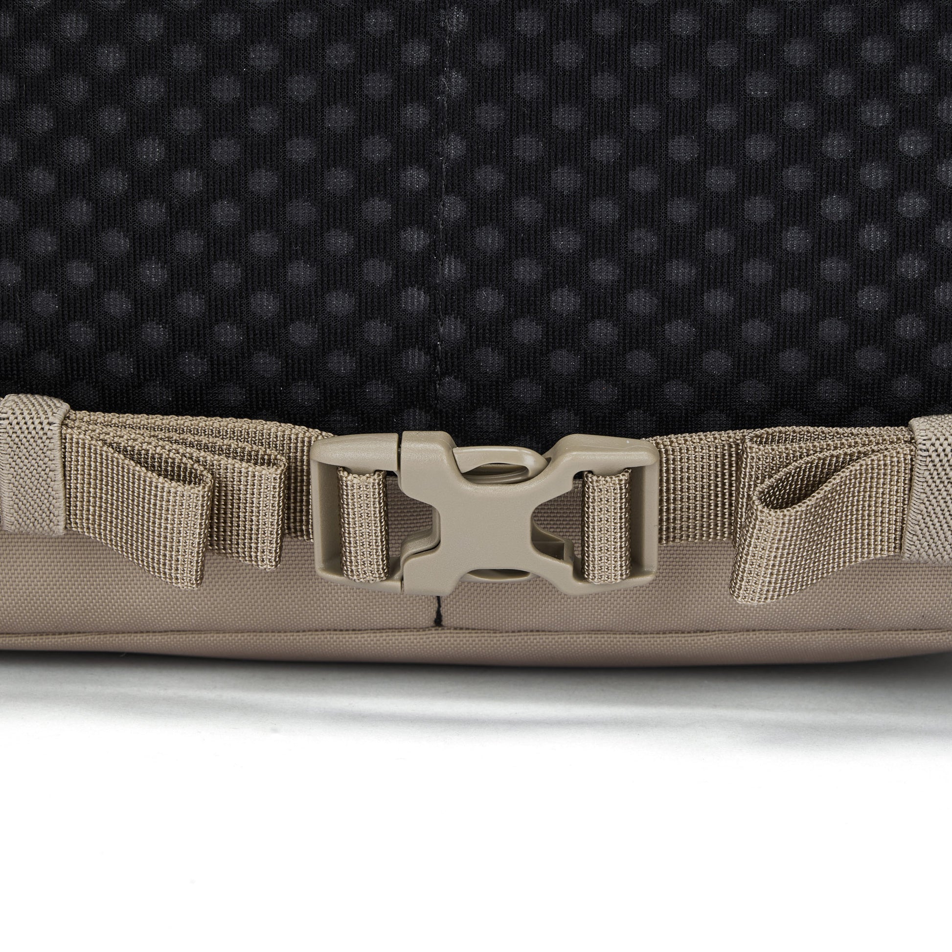 Close-up of a beige buckle on the Pacsafe® V 16L Anti-theft All-Around Backpack strap against black background.