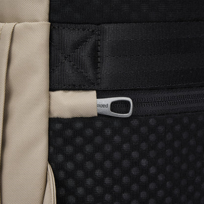 Close-up of beige strap and zipper on Pacsafe® V 16L Anti-theft All-Around Backpack in textured black.