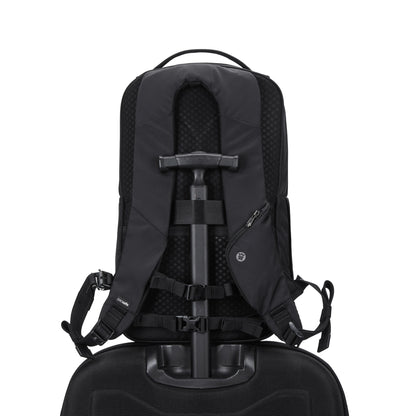 The Pacsafe® V 20L Anti-theft City Backpack is attached to a rolling suitcase, shown from the back.