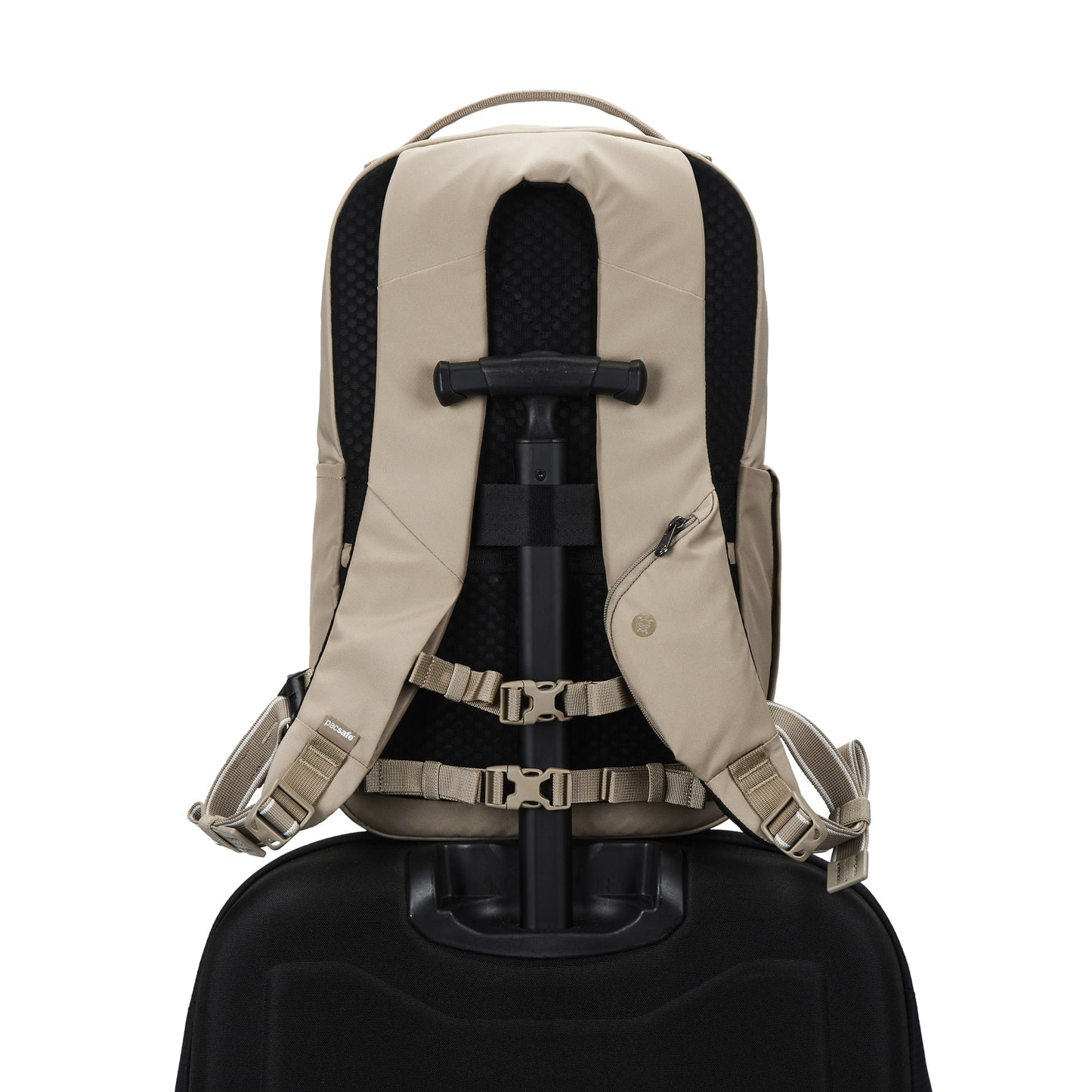 The Pacsafe® V 20L Anti-theft City Backpack in beige sits atop a black suitcase handle, viewed from behind.