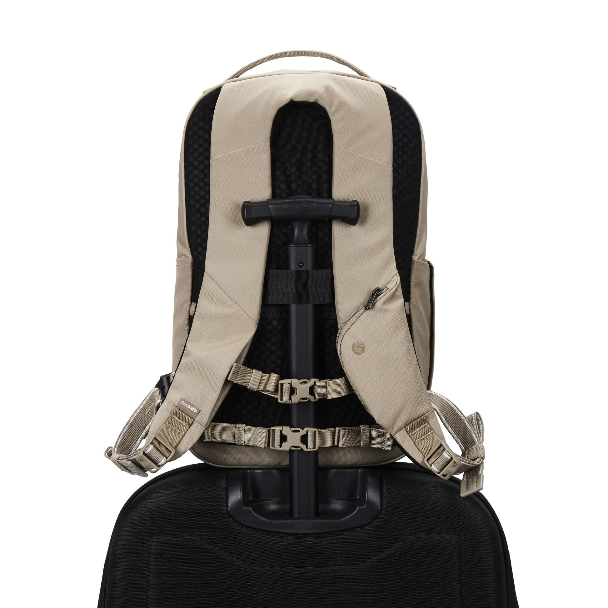 The Pacsafe® V 20L Anti-theft City Backpack in beige sits atop a black suitcase handle, viewed from behind.
