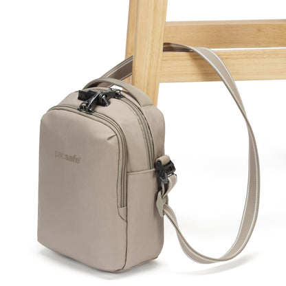 The Pacsafe® V Anti-theft Companion Crossbody by Pacsafe is strapped and locked to a chair leg for security.