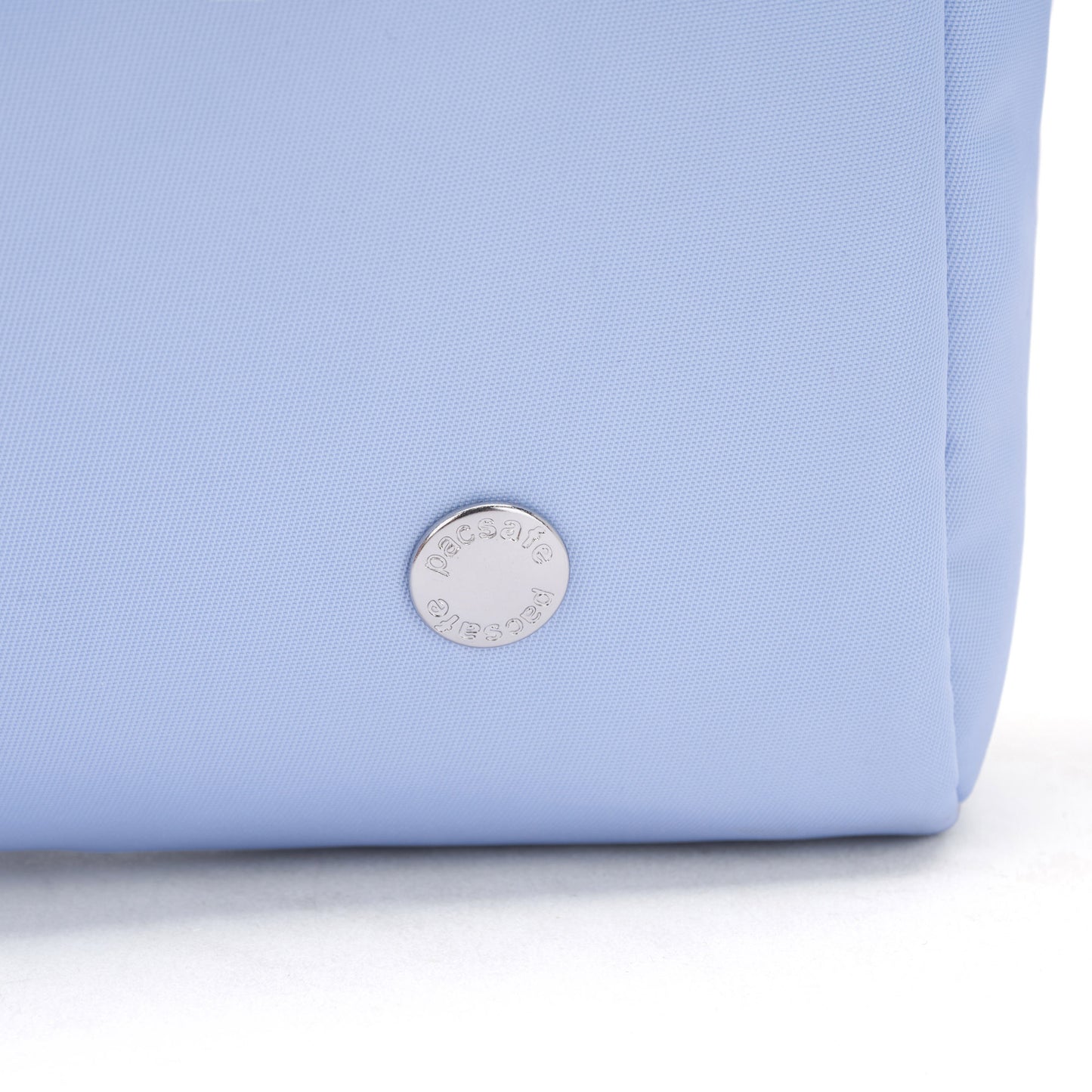 Close-up of the Pacsafe® W Anti-theft 3-in-1 Sling in light blue with a round silver emblem near the base.