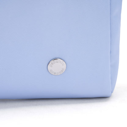 Close-up of the Pacsafe® W Anti-theft 3-in-1 Sling in light blue with a round silver emblem near the base.