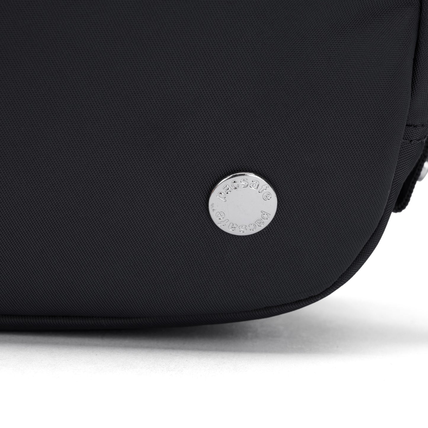 Close-up of the Pacsafe® W Anti-theft Micro Sling in black with a round silver Pacsafe logo badge near the bottom.