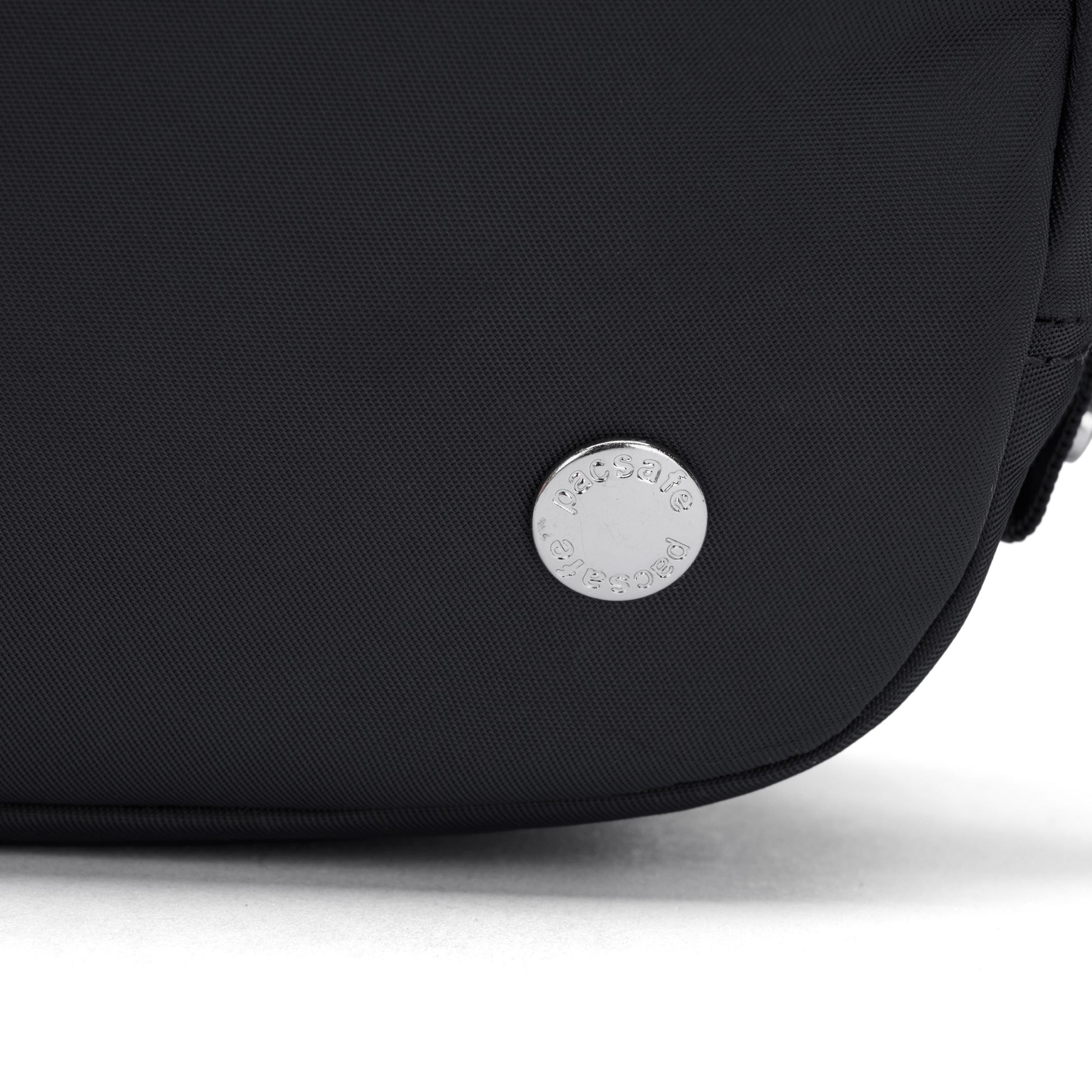Close-up of the Pacsafe® W Anti-theft Micro Sling in black with a round silver Pacsafe logo badge near the bottom.
