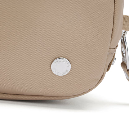 Close-up of the Pacsafe® W Anti-theft Micro Sling in beige with a round silver logo tag near the bottom.
