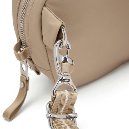 Close-up of the Pacsafe® W Anti-theft Micro Sling, a beige bag with striped strap, metal clasp, and RFID lock.