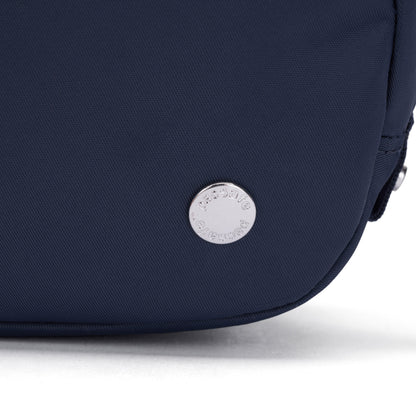 Close-up of the Pacsafe® W Anti-theft Micro Sling in navy blue with a round silver Pacsafe button on the corner.