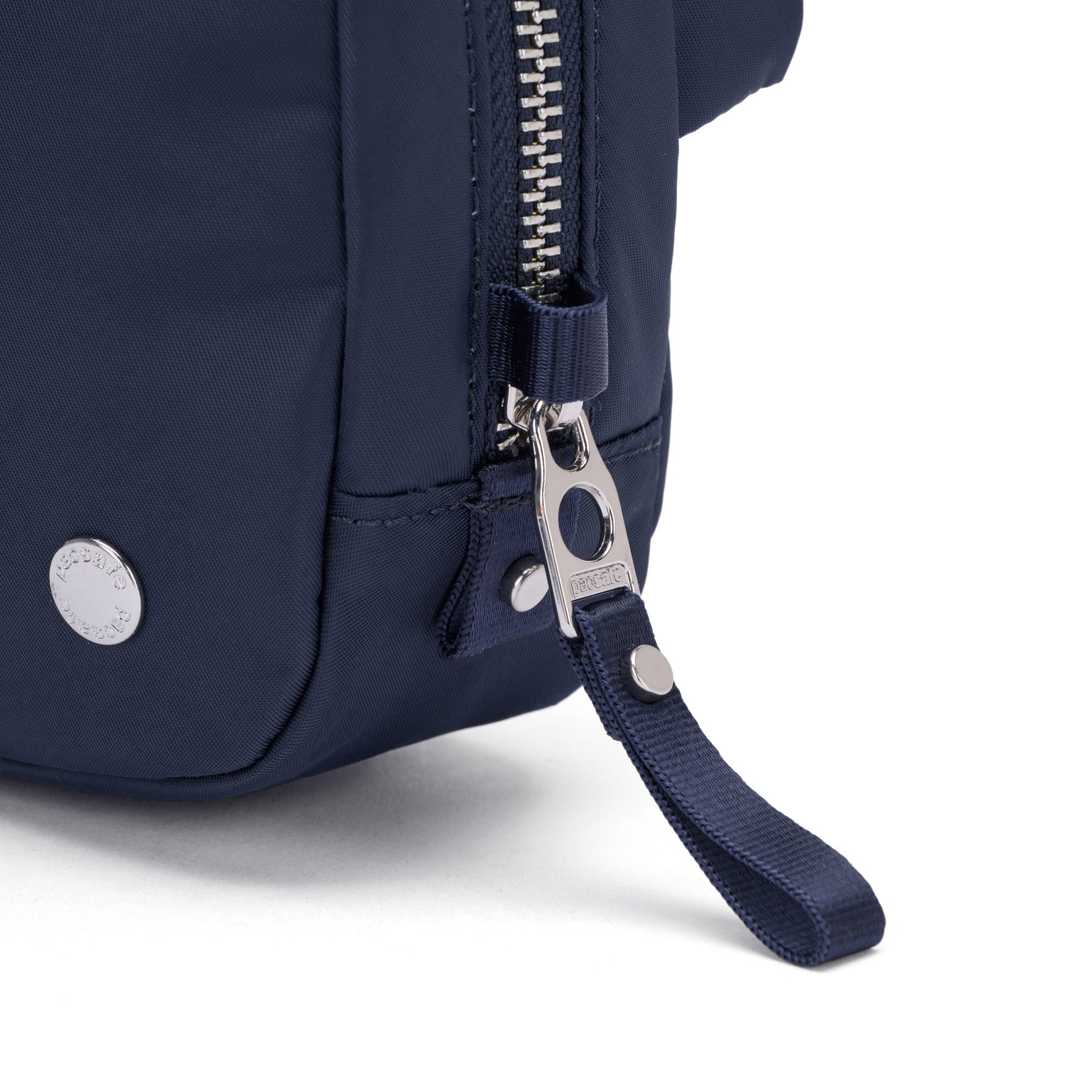 Close-up of the Pacsafe® W Anti-theft Micro Sling in navy, featuring a metal zipper and branded snap button.