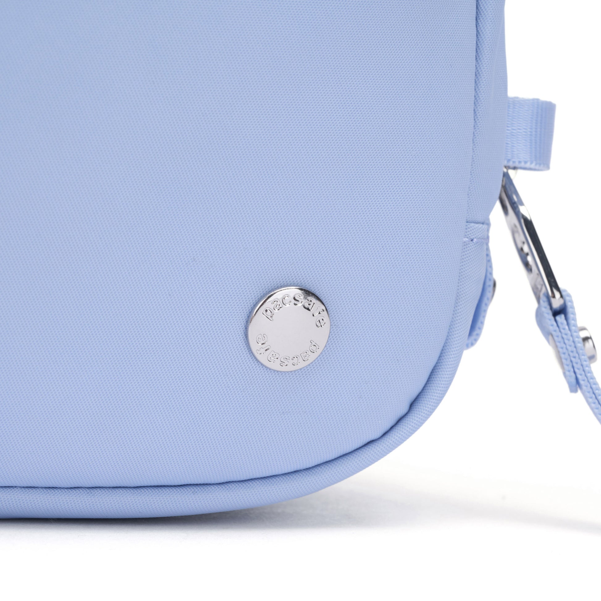 Close-up of the Pacsafe® W Anti-theft Micro Sling in light blue with a round silver logo and matching strap.