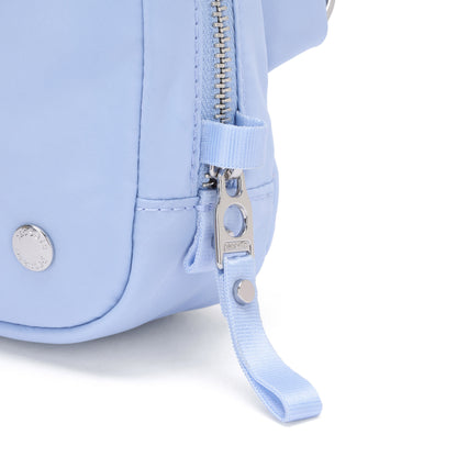 Close-up of the Pacsafe® W Anti-theft Micro Sling in light blue with silver zipper, button detail, and RFID blocking.
