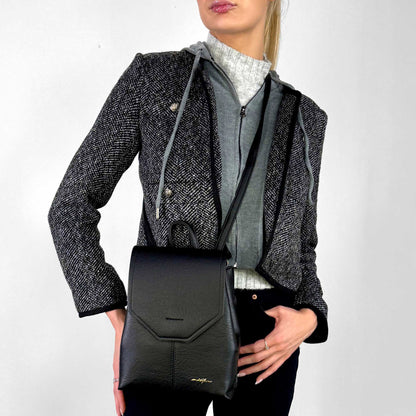 Woman wearing black houndstooth jacket and black Espe Raine Sling Bag, front view