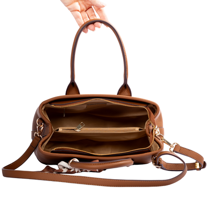 A hand holds the Miss Caprice Solana Handbag, showing its open top, compartments, and shoulder strap.