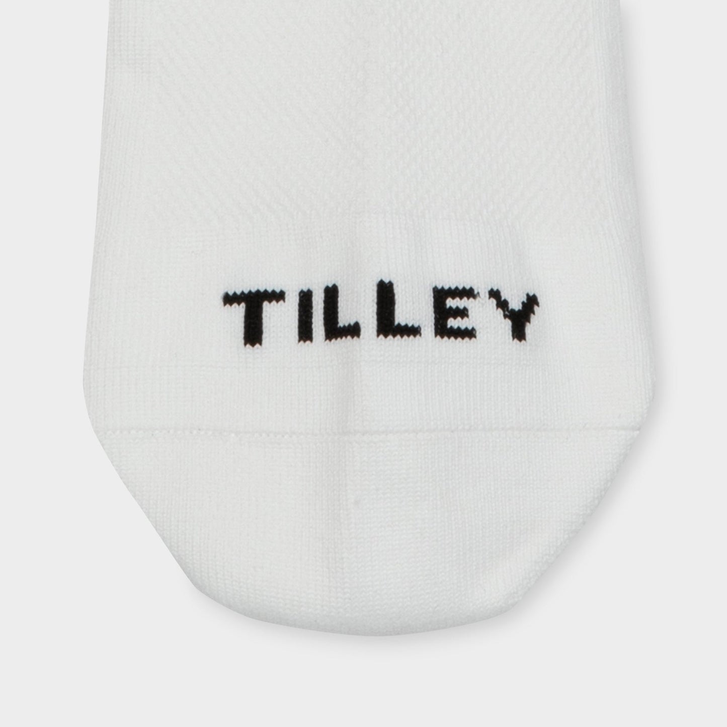 Tilley Ankle Travel Sock—white, moisture-wicking with "TILLEY" stitched in black near the toe.