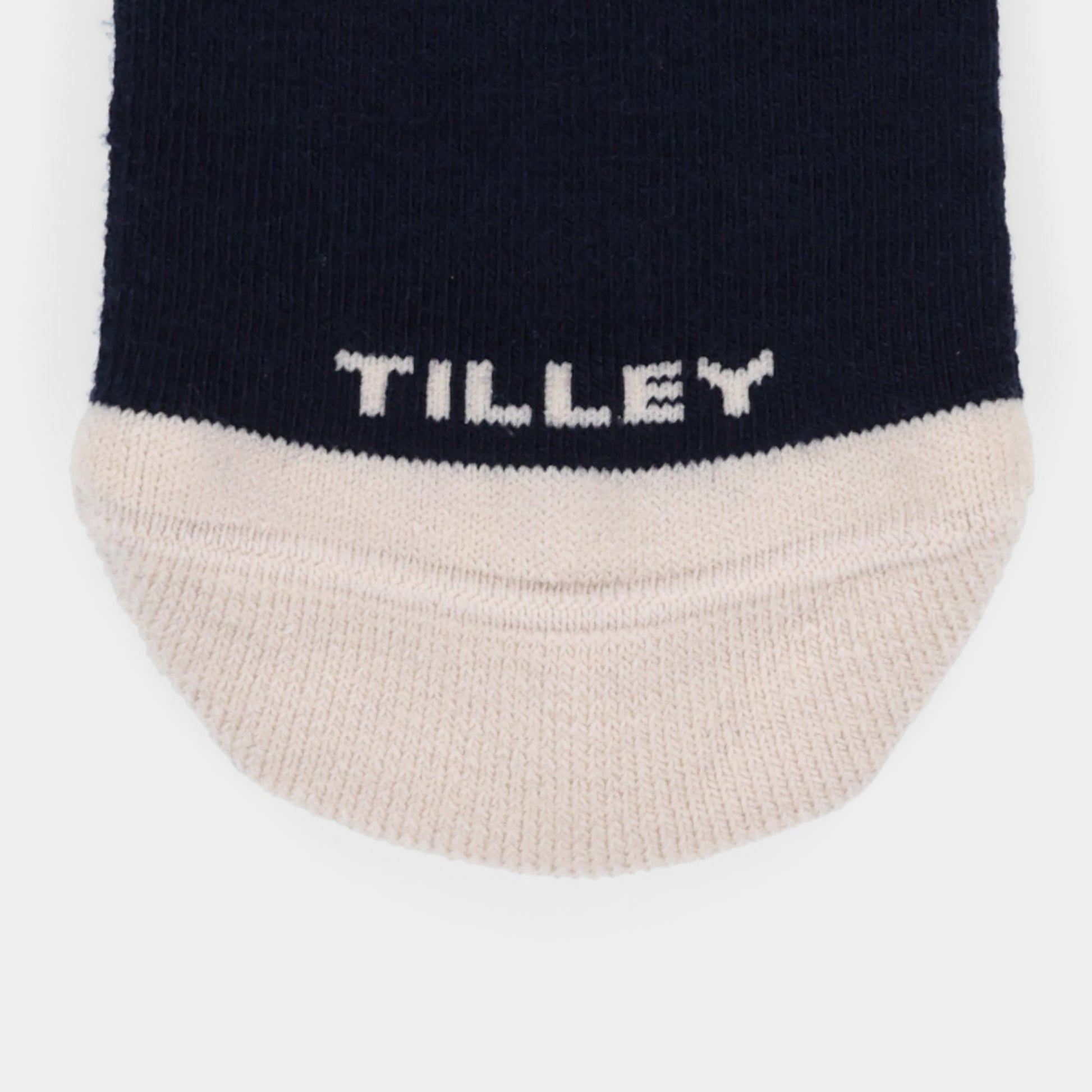 Close-up of Tilley Landscape Sock—navy merino, white toe, "TILLEY" print, and moisture-wicking. ONLINE ONLY.