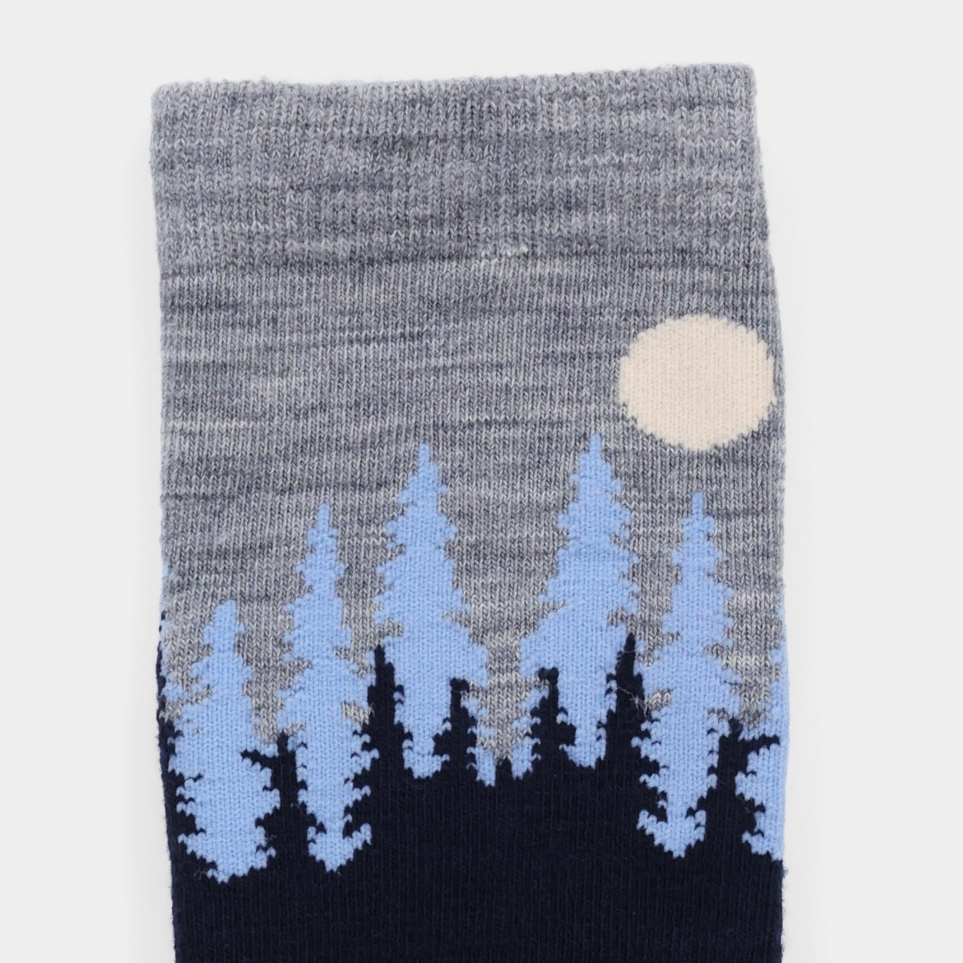Tilley Landscape Sock—gray merino with blue/black pine trees, white moon, and moisture-wicking comfort.