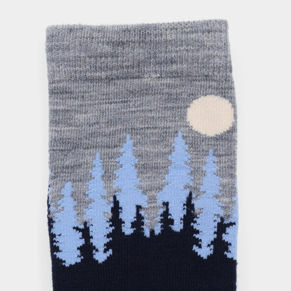 Tilley Landscape Sock—gray merino with blue/black pine trees, white moon, and moisture-wicking comfort.