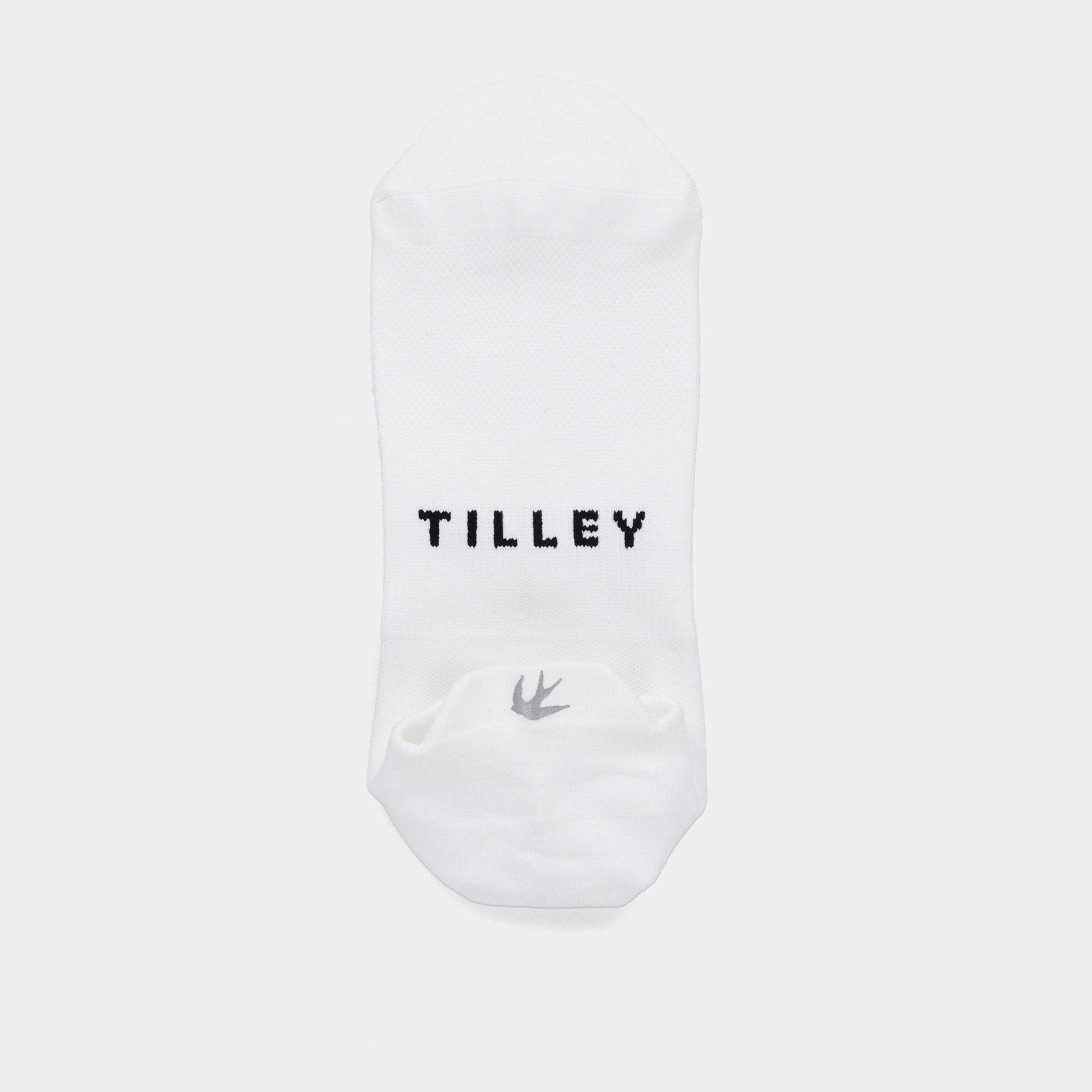 The Tilley Tab Travel Sock is a white ankle sock with arch support, black “TILLEY,” and a small bird logo.