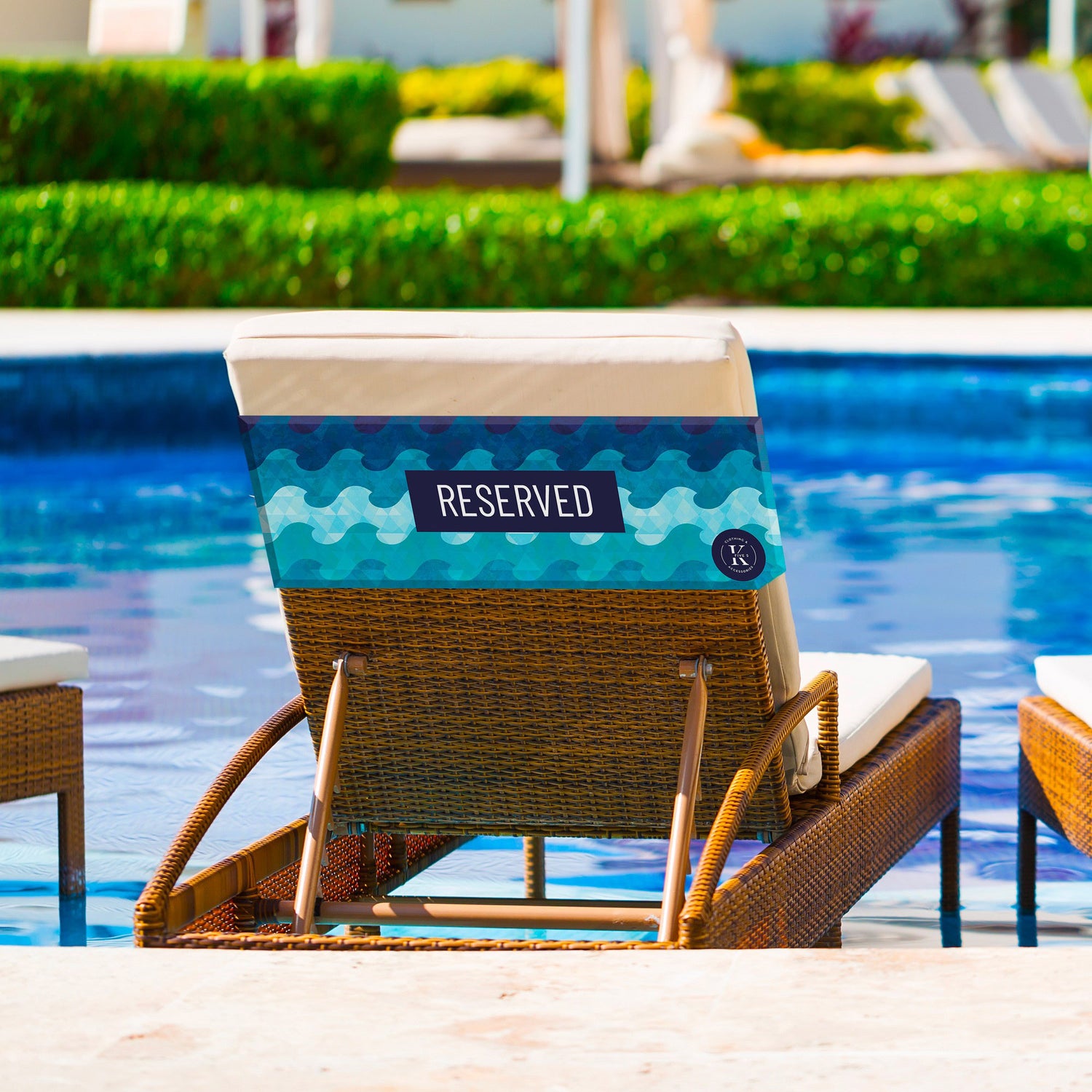 Wicker poolside lounge chair featuring a K5 Reserved Chair Sleeve by K5, set beside a swimming pool.