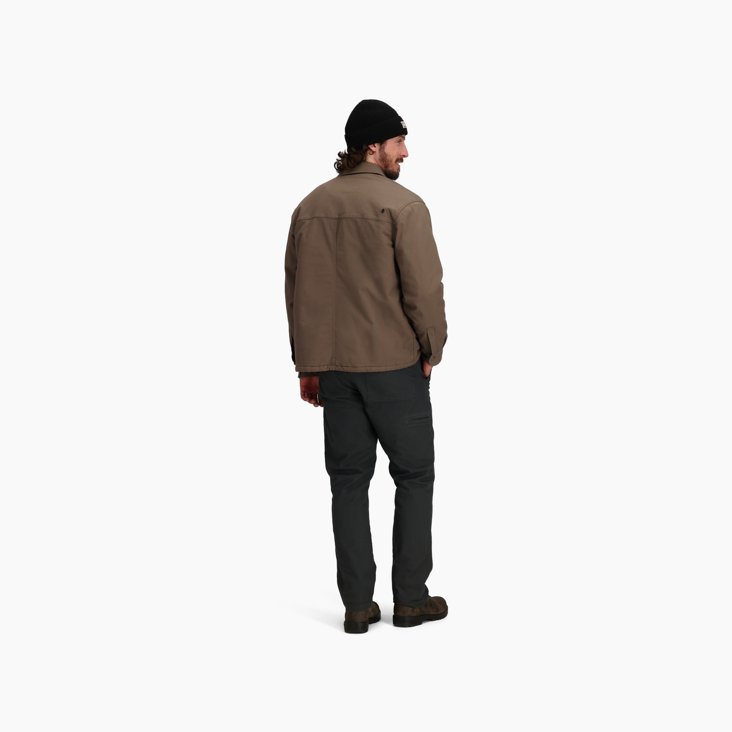 Man in Royal Robbins El Cap Canvas Shacket, black beanie, dark pants, glancing over shoulder on white background.
