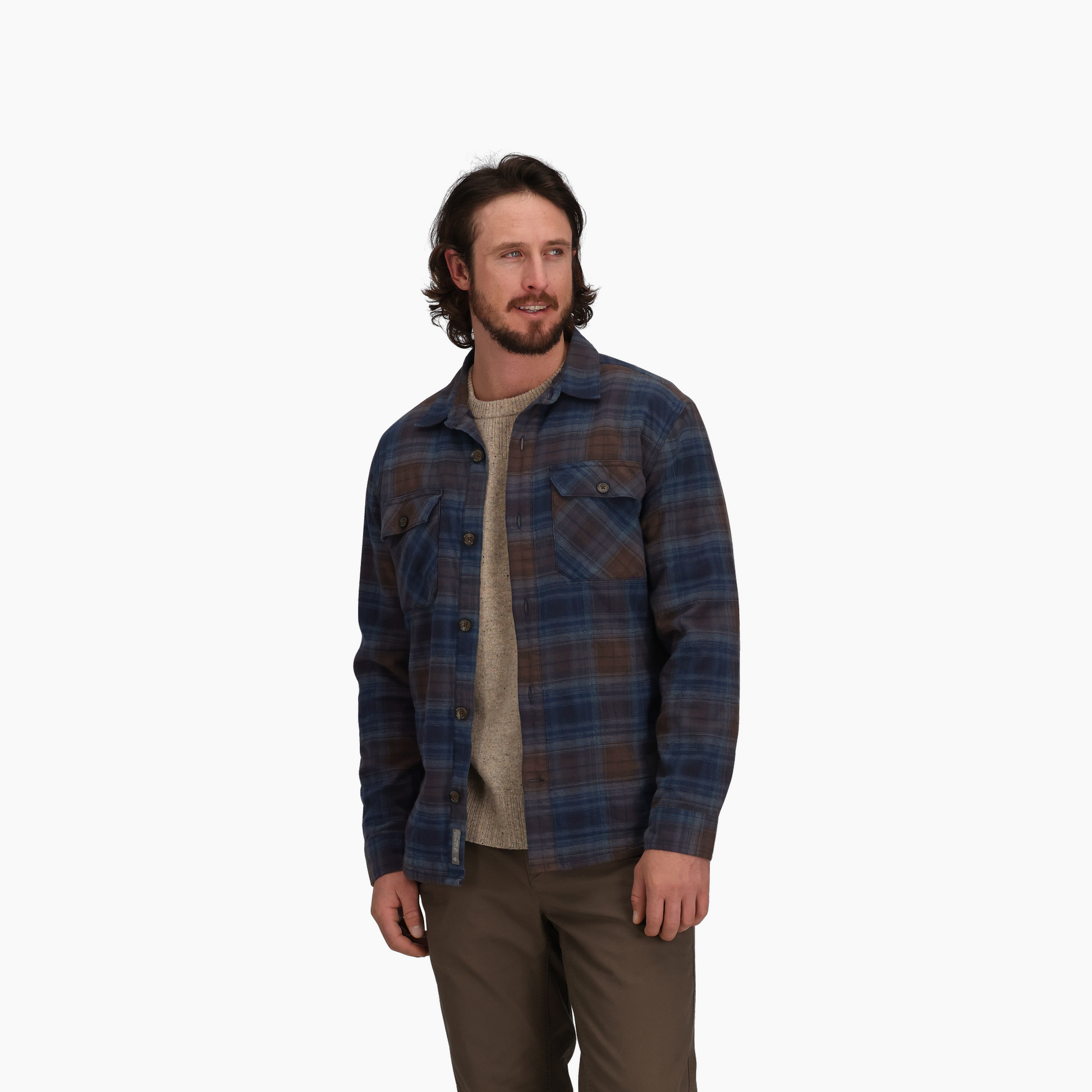 Man wearing Royal Robbins Men's Snowcap Lined Flannel shirt over a sweater and brown pants against white background.