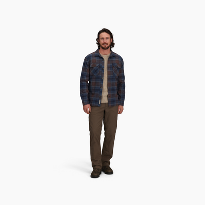 Man wears Royal Robbins Snowcap Lined Flannel shirt over beige tee, with brown pants and shoes, on white background.