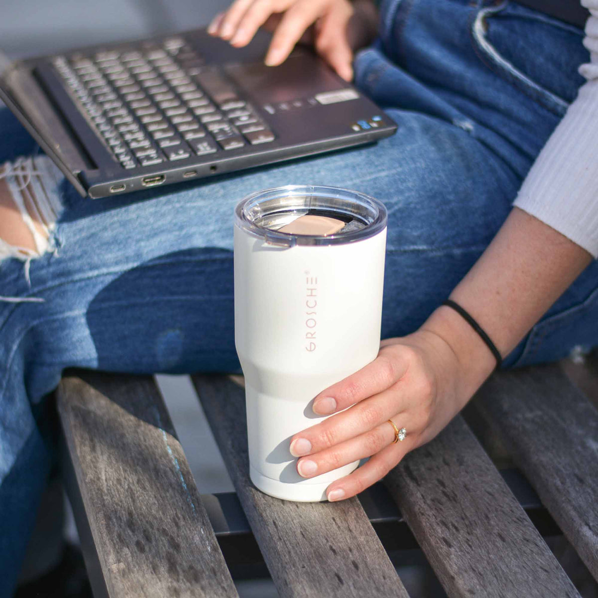 White Grosche Yukon travel mug on wooden slats beside jeans for outdoor work use