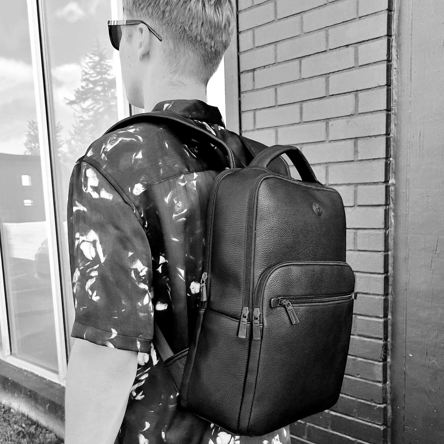 Black and white lifestyle image of back view of a man wearing short sleeve shirt and Espe Zak Backpack in black