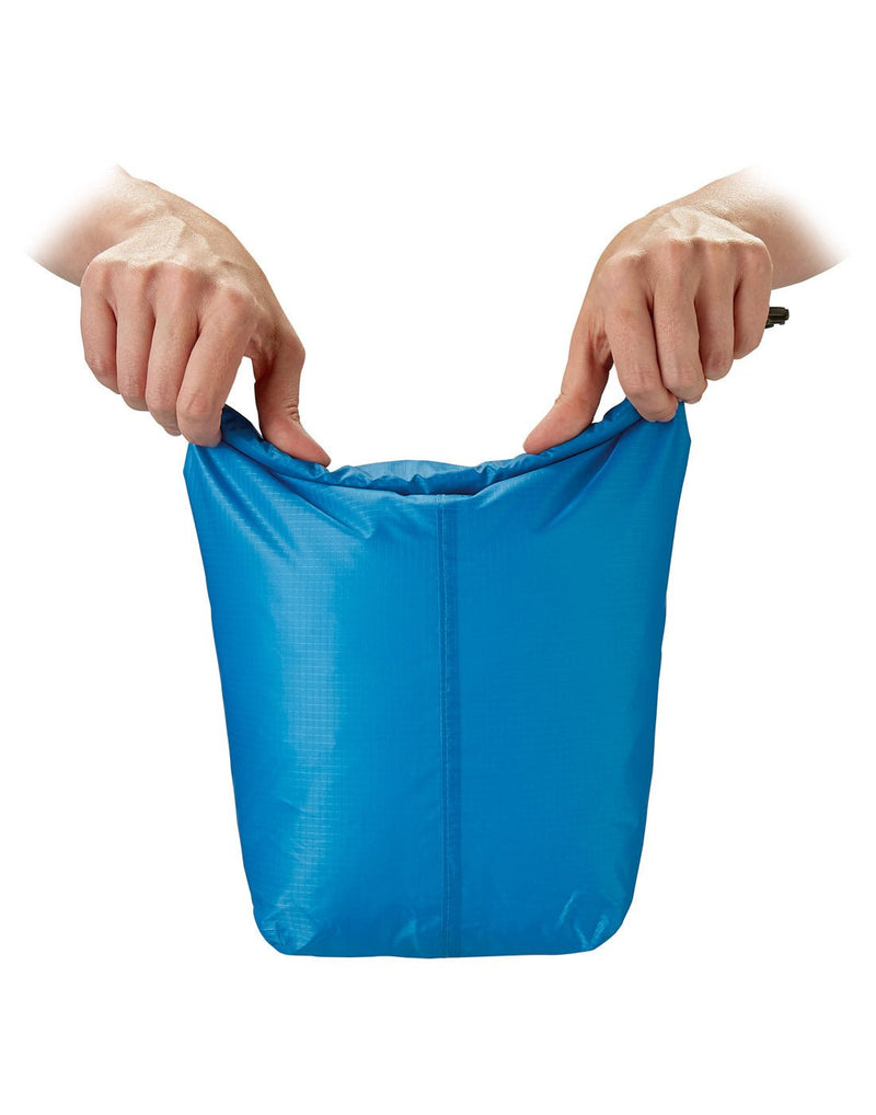 Front view of blue Go Travel Wet/Dry Bag, hands lifting bag from the top to  seal wet items from other contents.