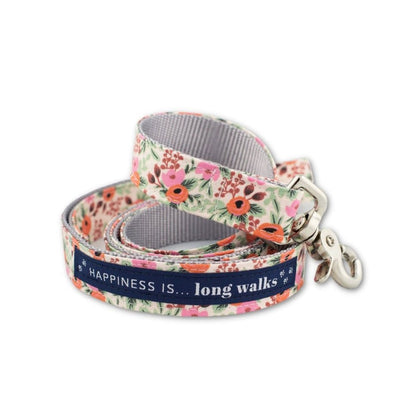 Happiness Is... Long Walks Floral Dog Leash coiled up, with silver clip and navy blue strip with white small paw prints and words that read Happiness Is...long walks 