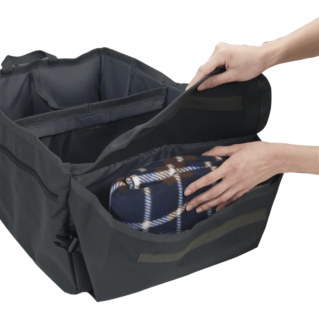 Side angle view of High Road® Trunk & Cargo Organizer, with hands placing blanket inside compartment.