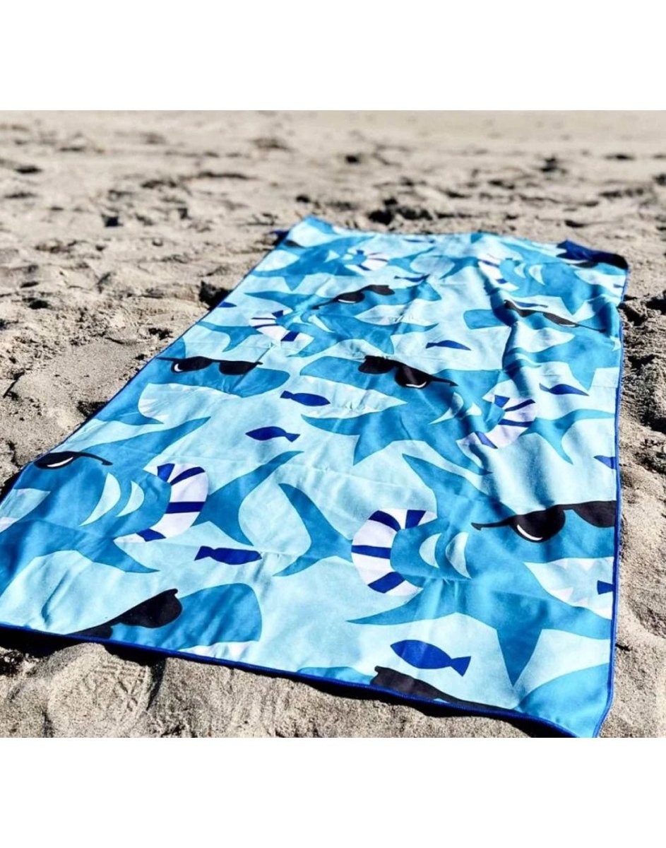 Lifestyle image of shark K5 Microfibre Beach Towel, laid out on sand.