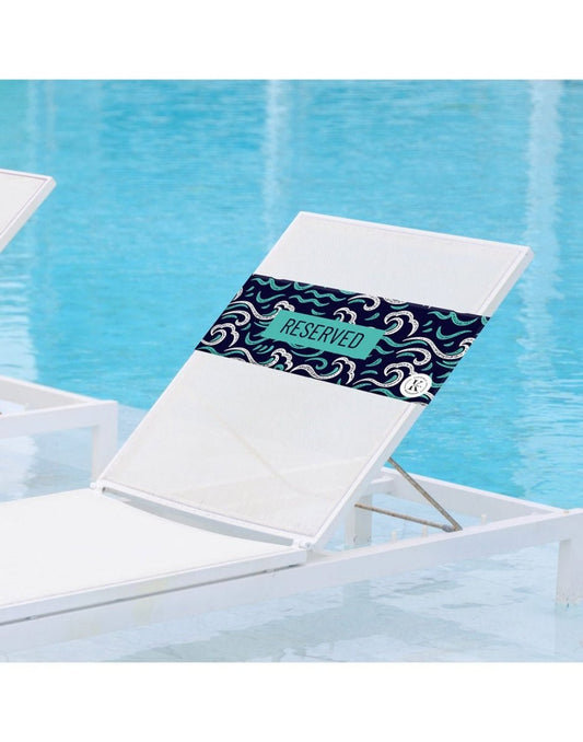 Product Image – Lifestyle image of ocean K5 Reserved Chair Sleeve, placed on a poolside chair with pool visible in the background.