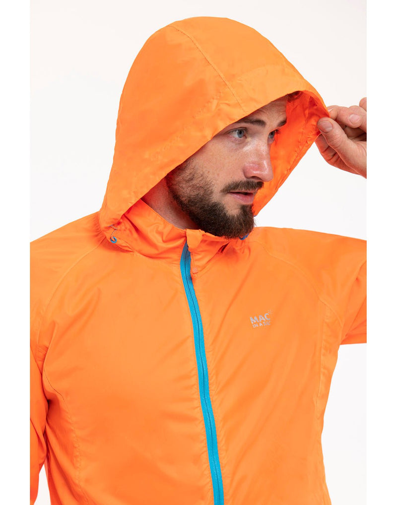 Close up of man wearing Mac in a Sac Origin II Neon Packable Waterproof Jacket in neon orange, with the hood over his head.