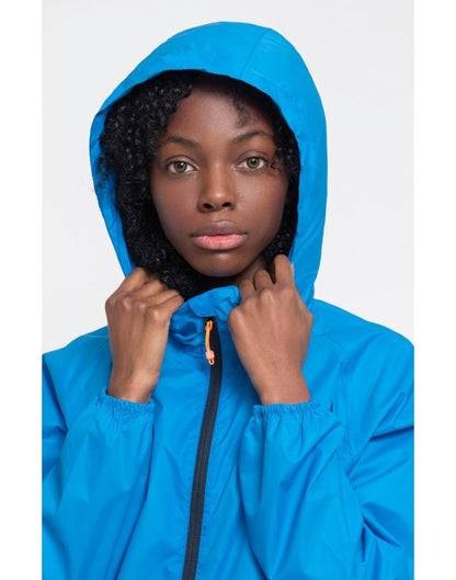 Close up of woman wearing Mac in a Sac Origin II Packable Waterproof Jacket in ocean view, with hood over her head.