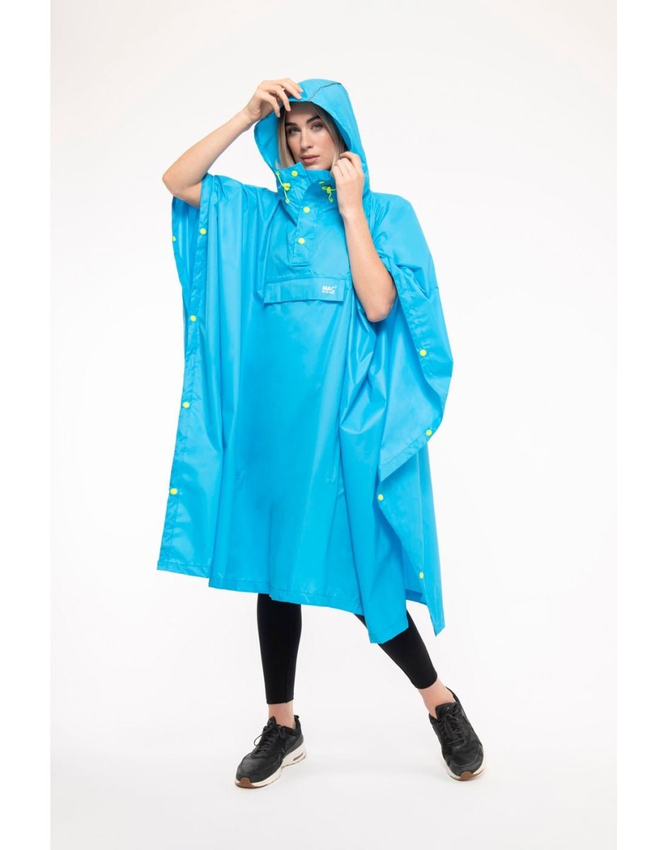 Woman wearing Mac in a Sac Packable Waterproof Poncho in neon blue, front angle view with hands holding hood.