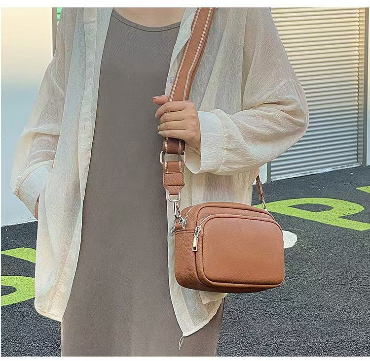 Lifestyle image of woman wearing taupe dress with white shirt on top and the tan Alina's Front Pocket RFID Crossbody over one shoulder