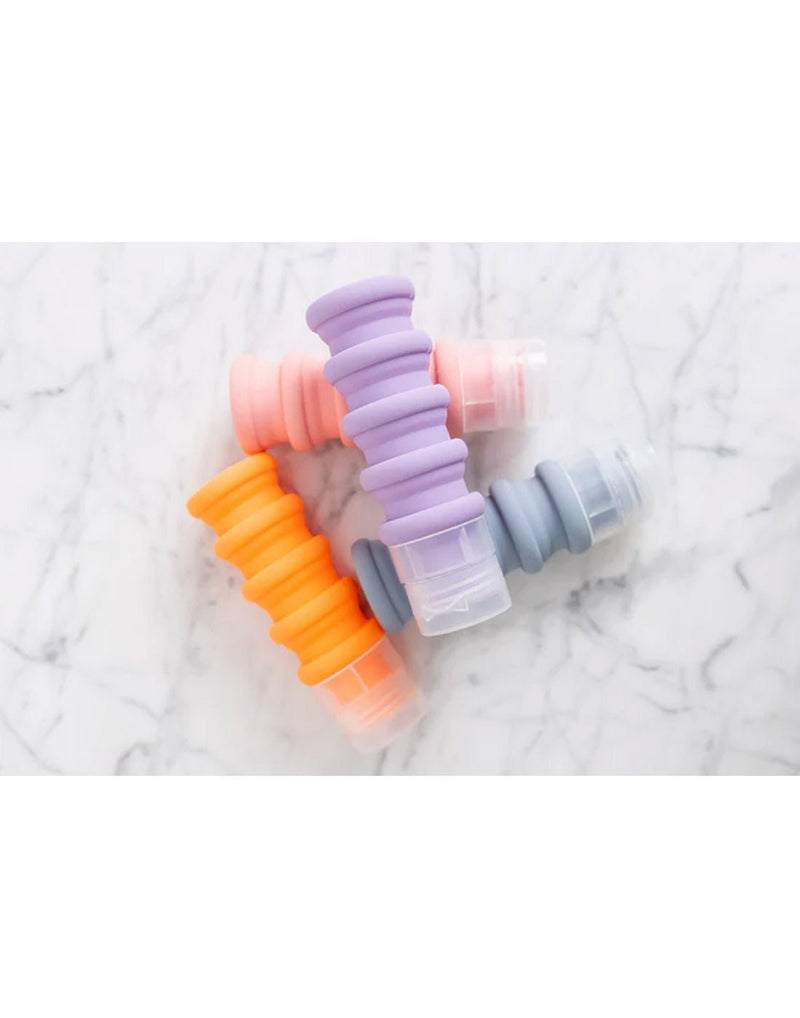 Lifestyle image of MyTagAlongs Set of 4 Expandable Silicone Travel Bottles in vibrant pastels, positioned diagonally. 